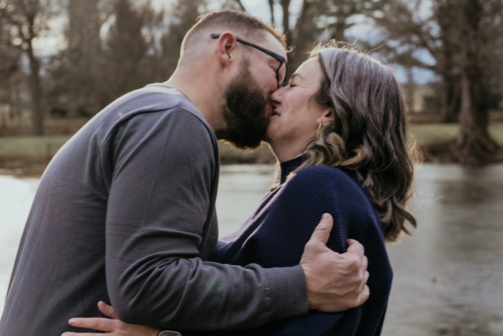photo of a couple holding each other in front of a lake