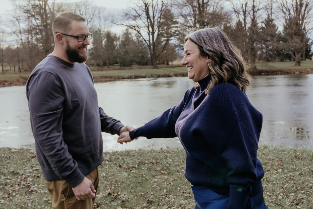 photo of a couple holding hands in front of a lake